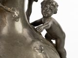a silver vase with a little boy on top of it