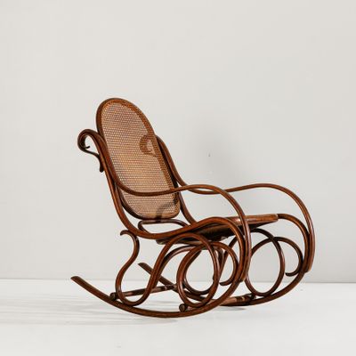un fauteuil à bascule en bois avec un dossier en rotin et une assise en osier
