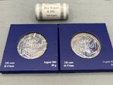 deux pièces d'argent dans une boîte bleue, avec un rouleau de billets en arrière-plan