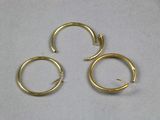 trois paires de boucles d'oreilles créoles en or posées sur une surface blanche