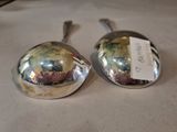 two silver spoons with tags on them on a table