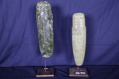 une paire de sculptures en pierre sculptées, posées sur des socles, sur fond bleu