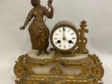 une statue représentant une femme tenant un oiseau à côté d'une horloge