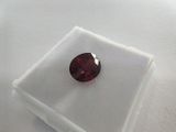 a close up of a red garnet stone on a white surface