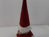 un petit Père Noël en peluche assis sur une surface blanche