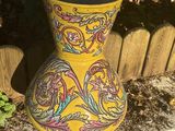 a yellow vase sitting on the side of a wooden fence