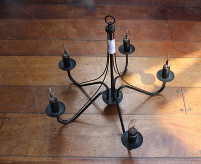 un lustre noir à cinq lumières posé sur un parquet