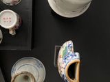 a black table with a bunch of cups and saucers on it