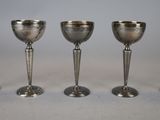 four silver goblets are lined up in a row on a table