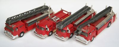 quatre camions de pompiers rouges alignés sur une surface blanche