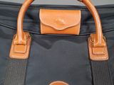 a close up of a black bag with a brown handle