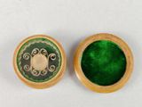 deux petites boîtes en bois, dont l'intérieur est recouvert de velours vert, posées sur une surface blanche