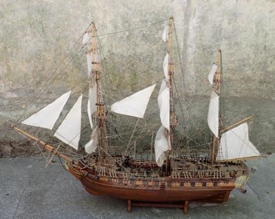 une maquette en bois d'un voilier posée par terre