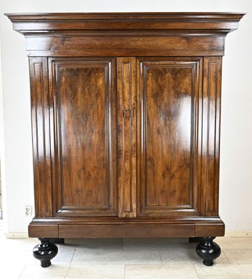 une grande armoire en bois à deux portes, montée sur roulettes