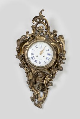 a gold clock on the wall with a white background