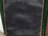 an old blackboard sitting on the ground next to a green curtain