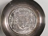 a silver plate with a picture of a coat of arms on it