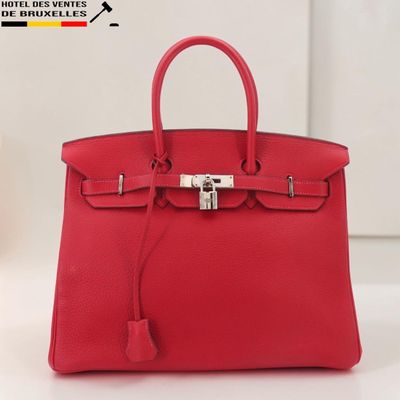 un sac à main en cuir rouge posé sur une table blanche