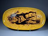une assiette jaune et noire sur laquelle est représenté un lézard