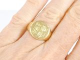 a gold signet ring on a person ' s hand