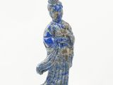 une statue bleue et blanche représentant une femme tenant une fleur