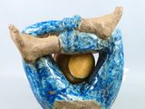 a ceramic sculpture of a man holding a banana in his hand