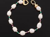 a white pearl bracelet with emerald and gold beads