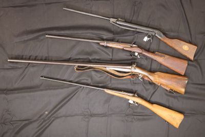 five guns are lined up on a black cloth on a table