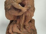 a small statue of a woman sitting on a rock