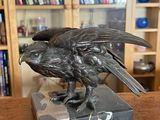 une statue représentant un oiseau perché sur un bloc de marbre