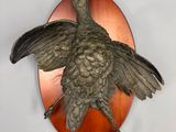 un oiseau en bronze accroché au mur d'une pièce