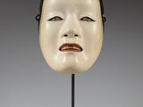 a close up of a mask on a stand with a gray background