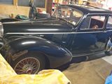 une voiture noire garée dans un garage, à côté d'une couverture jaune