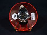 a watch sitting inside of a glass bowl on a black surface
