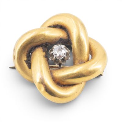 an image of a gold knot brooch with a diamond in the center