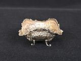 an antique silver plate with a bird on it on a black surface