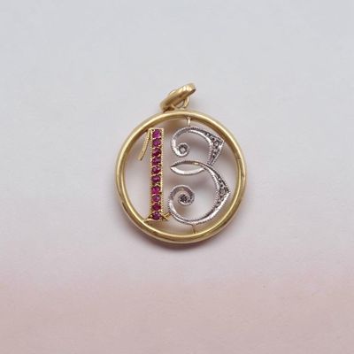 a close up of a gold and silver pendant with a bird on it