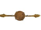 un gros plan d'une pièce de monnaie sur une broche en forme de flèche en or