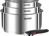 trois casseroles en acier inoxydable et une télécommande posée devant elles