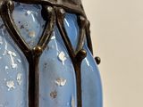 a blue glass vase with a metal handle on a table