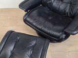 an image of a black leather chair and ottoman on a wooden floor