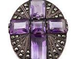 un gros plan d'un pendentif en forme de croix en pierre violette sur fond blanc