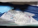 a mesh bag with clothes inside of it on a bed