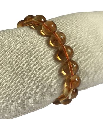 bracelet en perles de verre marron posé sur une serviette posée sur une nappe blanche