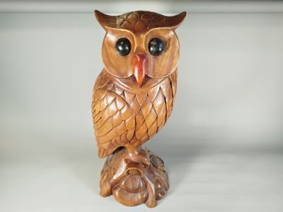 un hibou en bois perché sur une souche d'arbre