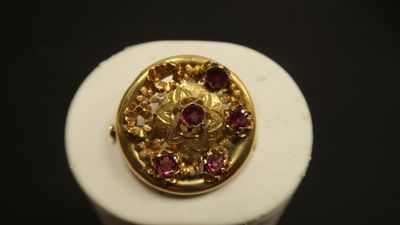 Gros plan sur une bague en or ornée de pierres roses