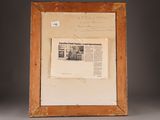 an old picture frame with a newspaper and a piece of paper on it