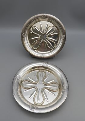 a pair of silver plated ashtrays on a table