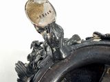 a close up of a silver vase with a bird on it
