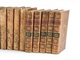several old books are lined up in a row on a white surface